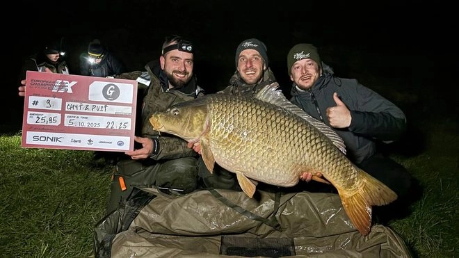 Muži drží velkou kapra s certifikátem o ulovení ryby.