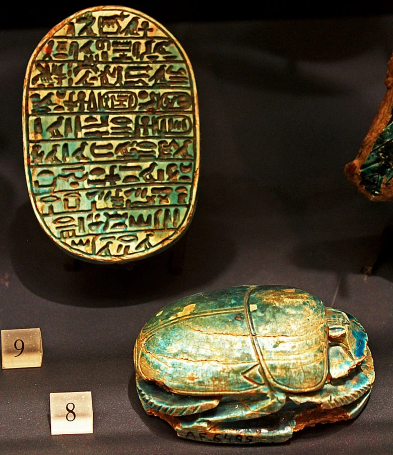 Egypatský skarabeus z turkusu s kartouchem napsaným hieroglyfem.