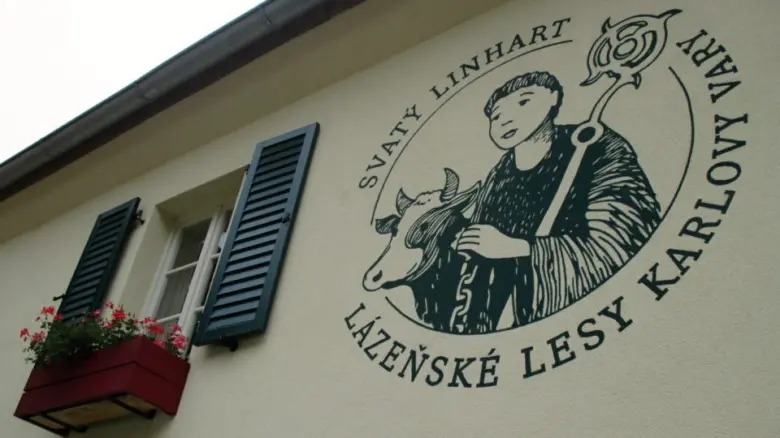 Fotografie budovy s ilustrací svatého Linharta a býka.