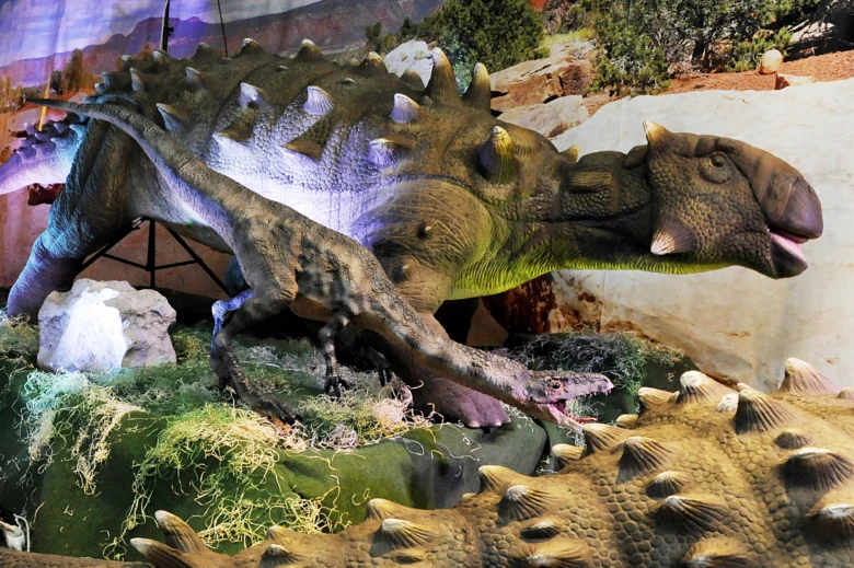 Model dinosaura v expozici pro děti s realistickým terénem.