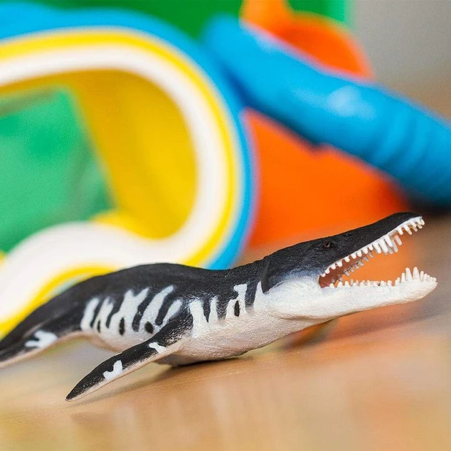 Figurína pravěkého mořského plazu plesiosaury na dřevěné ploše.